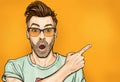 Amazed fashionable guy in glasses with open mouth, stares aside, shows something strange and unexpected. Royalty Free Stock Photo