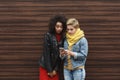 Amazed female friends with smartphone outdoors