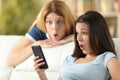 Amazed friends checking phone online news at home