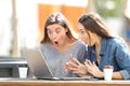 Amazed friends finding online content on laptop in a park Royalty Free Stock Photo