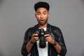 Amazed handsome afro american man in leather jacket holding digital camera