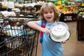 Amazed kid with shopping cart with sweets cake at grocery store or supermarket.