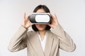 Amazed office woman, asian business person in suit, wearing vr headset, looking at smth in virtual reality glasses with