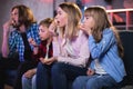 Amazed parents with children watching TV and eating popcorn Royalty Free Stock Photo