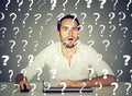 Perplexed man working on desktop computer has many questions Royalty Free Stock Photo