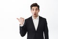 Amazed realtor, businessman in suit pointing finger left, showing banner on copyspace with wow face, gasping impressed Royalty Free Stock Photo