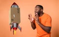 Amazed and shocked expression of a boy who receives a package. orange background