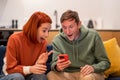 Amazed shocked happy man woman rejoicing looking at smartphone screen at home. Royalty Free Stock Photo