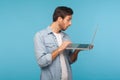 Amazed shocked man in worker denim shirt doing freelance job on laptop, typing email or surfing internet