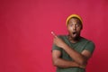 Amazed, shocked pointing one finger sideways with hands folded young african american man wearing khaki, green t-shirt and yellow Royalty Free Stock Photo