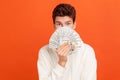 Amazed shocked teenager in casual white sweater with hood hiding behind hundred dollars fan, rich youth, lottery victory