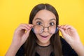 Amazed smart girl child with long hair and eyeglasses on yellow background, surprise Royalty Free Stock Photo