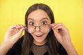 amazed smart girl child with long hair and eyeglasses on yellow background, surprise Royalty Free Stock Photo
