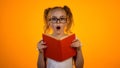 Amazed smart girl in glasses holding book and looking to cam, interesting story Royalty Free Stock Photo