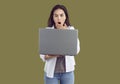 Amazed surprised woman is looking at screen of laptop on khaki background with wide opened eyes. Royalty Free Stock Photo