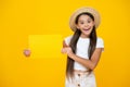 amazed teen girl hold empty advertisement paper with copy space on yellow background