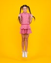 Amazed teenager. Excited teen girl. Full length funny teenager kid jump enjoy rejoice win isolated on yellow background Royalty Free Stock Photo