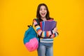Amazed teenager. School girl hold copybook and book on yellow isolated studio background. School and education concept Royalty Free Stock Photo