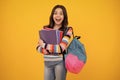 Amazed teenager. School girl hold copybook and book on yellow isolated studio background. School and education concept Royalty Free Stock Photo