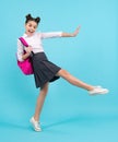 Amazed teenager. Schoolgirl in school uniform with school bag. Teenage girl student on blue background. Jump