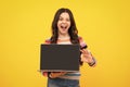 Amazed teenager. Student school girl with laptop on isolated studio background. Screen of laptop computer with copyspace