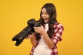 Amazed teenager. Teenager girl with dslr photo camera with zoom lens. Child photographer isoalted on yellow background Royalty Free Stock Photo