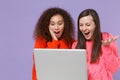 Amazed two young european african american women friends in knitted sweaters isolated on violet purple background studio Royalty Free Stock Photo