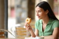 Amazed woman eating delicious doughnut in a bar