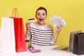 Amazed woman workplace with laptop, holding dollars and credit card, looking at camera with smile. Royalty Free Stock Photo