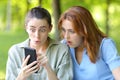 Amazed women checking phone content in a park