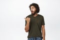 Amazed young arab man with beard, pointing and looking left with surprised face, standing in clothes over white Royalty Free Stock Photo