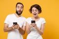 Amazed young couple friends bearded guy girl in white blank empty t-shirts isolated on yellow orange background. People Royalty Free Stock Photo