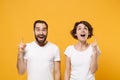 Amazed young couple friends bearded guy girl in white blank empty t-shirts posing isolated on yellow orange wall Royalty Free Stock Photo