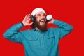 Amazed young man with beard listening music at headphones and wearing santa claus hat Royalty Free Stock Photo