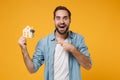 Amazed young man in casual blue shirt posing isolated on yellow orange wall background, studio portrait. People