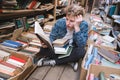 Amazed young man sitting on the floor in a public library and reading a book Royalty Free Stock Photo