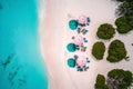 Amazing aerial view of paradise beach landscape with loungers and pink umbrellas close to amazing tropic sea. White sand and blue