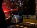 Amazing atmosphere during night while driving on a rainy street with closeup of red car street lights and drops of rain in focus Royalty Free Stock Photo