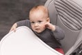 Amazing baby boy in baby chair looking at camera. Cute infant thoughtful kid.