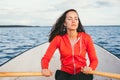 Amazing beautiful haired girl swims on a wooden boat and rowing with oars in the gorgeous spring lake. Lifestyle without