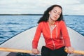 Amazing beautiful haired girl swims on a wooden boat and rowing with oars in the gorgeous spring lake. Lifestyle without