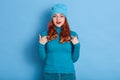 Amazing beautiful lady indicates at her self, wearing casual blue shirt over blue background, wears red lips, keeps mouth