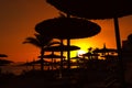 Amazing beautiful red sunset on the sea coast. Dark silhouettes of beach umbrellas Royalty Free Stock Photo