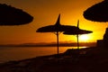 Amazing beautiful red sunset on the sea coast. Dark silhouettes of beach umbrellas Royalty Free Stock Photo