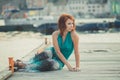 Amazing beautifull lady girl woman with red flame hair wearing fancy fashion green clothes posing sitting on wooden pier jetty wth