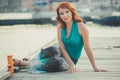 Amazing beautifull lady girl woman with red flame hair wearing fancy fashion green clothes posing sitting on wooden pier jetty wth