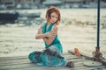 Amazing beautifull lady girl woman with red flame hair wearing fancy fashion green clothes posing sitting on wooden pier jetty wth