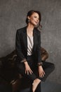 Amazing beauty, a gorgeous model girl with perfect makeup and hairdo in stylish suit posing in the vintage armchair Royalty Free Stock Photo