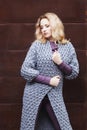 Amazing blonde girl posing in a gray knitted coat on the street on a background of rusty metal wall. fashion. beauty Royalty Free Stock Photo