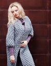 Amazing blonde girl posing in a gray knitted coat on the street on a background of rusty metal wall. Fashion. Beauty. Royalty Free Stock Photo